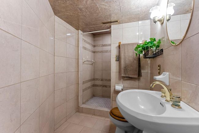 An updated ¾ bathroom, situated next to the den, includes stylish tile flooring and a spacious walk-in tiled shower for ultimate relaxation. | Image 17