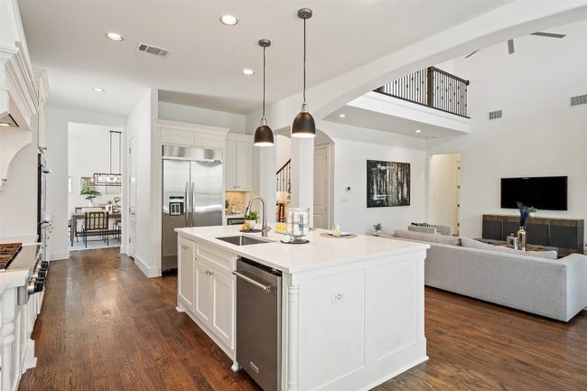 Kitchen featuring appliances with stainless steel finishes, arched walkways, open floor plan, white cabinetry, and dark wood-style floors | Image 5