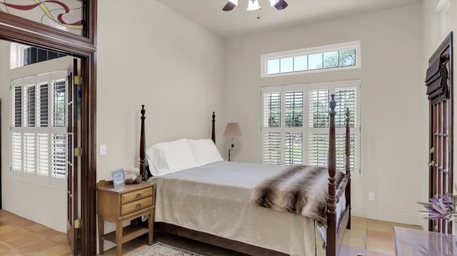 Secondary North Bedroom 3 featuring a ceiling fan, saltillo tile floors and transome window. This room has a covered outside entry. | Image 36
