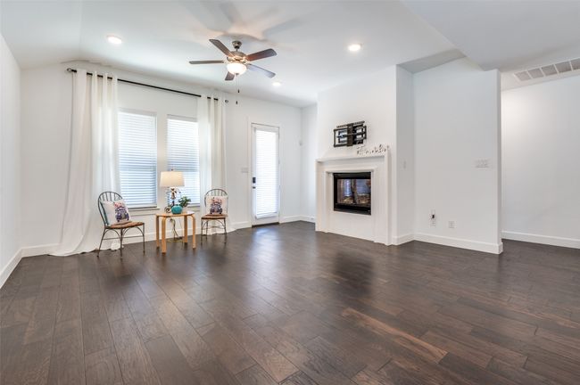 The living room features elegant dark wood-style flooring, a glass-enclosed fireplace, a ceiling fan, and baseboards. | Image 12
