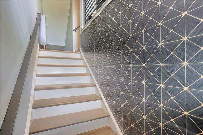 A bold geometric accent wall adds a touch of modern flair to this stairway, creating a striking first impression as you move through the home. | Image 4