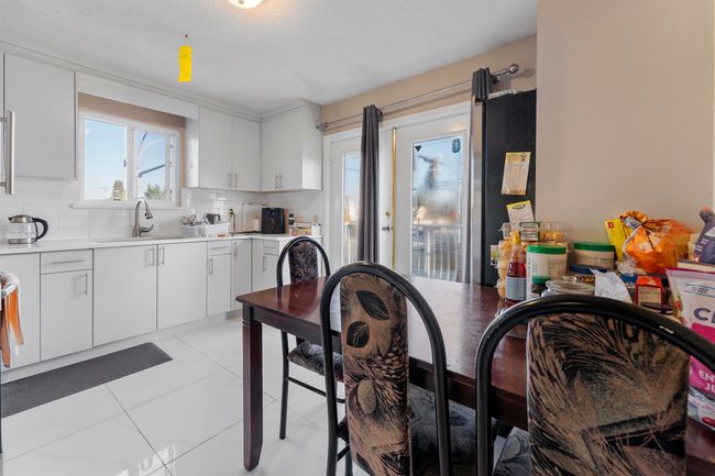 Kitchen with light countertops, white cabinets, decorative backsplash, and a sink | Image 11