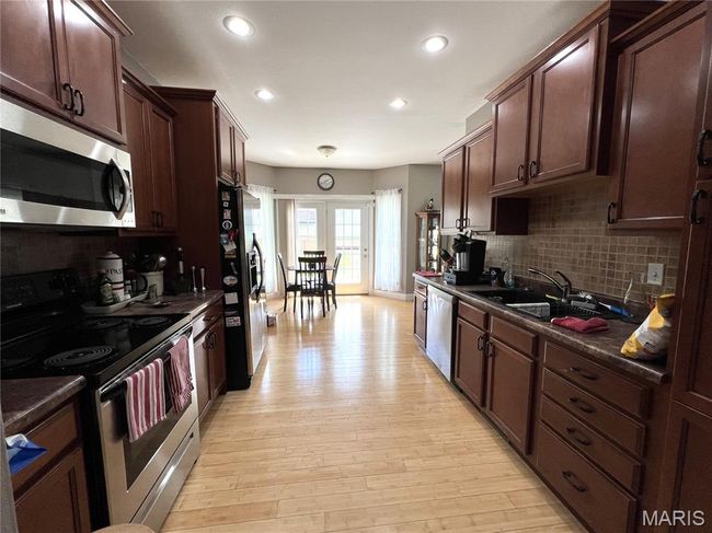 Kitchen featuring appliances with stainless steel finishes, dark countertops, backsplash, light wood finished floors, and recessed lighting | Image 8