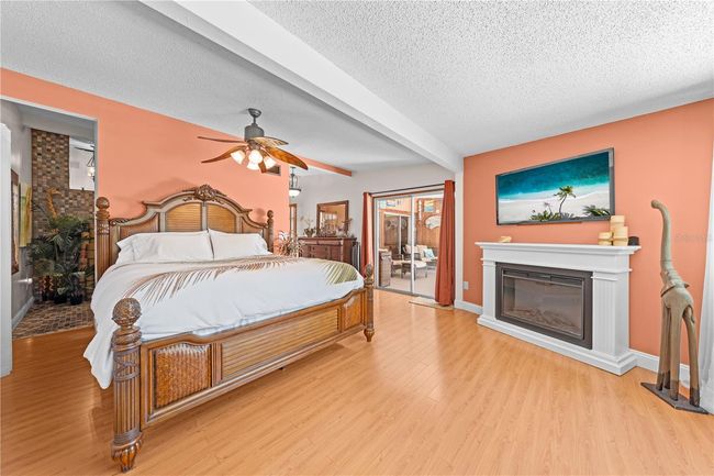 Main Home - Primary Bedroom with an electric fireplace and sliding glass doors that lead out to the lanai and pool/spa. | Image 47