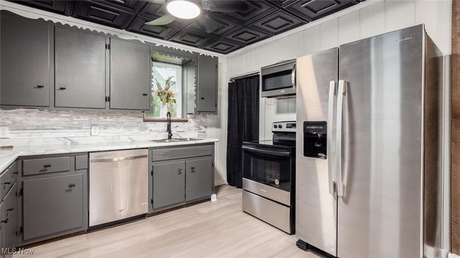 Kitchen with appliances with stainless steel finishes, gray cabinetry, ceiling fan, an ornate ceiling, and light wood-style floors | Image 7