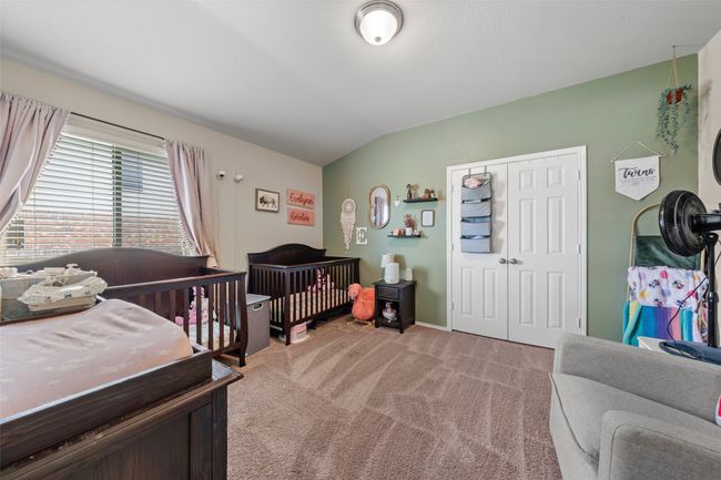 Bedroom with light colored carpet, a closet, a crib, and lofted ceiling | Image 9