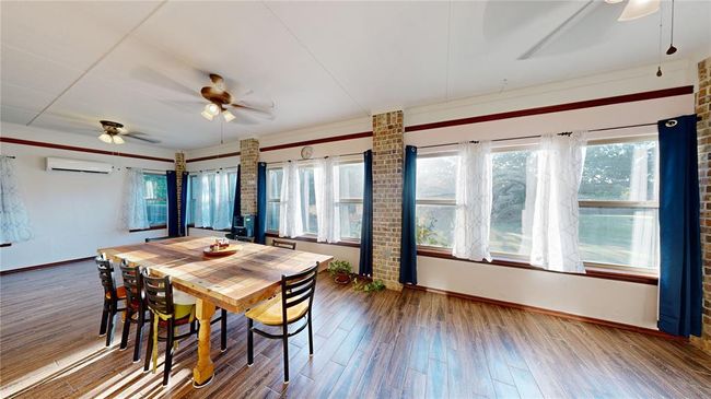 Dining space with baseboards, a ceiling fan, wood finished floors, and a wall mounted AC | Image 26