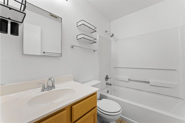 Bathroom featuring toilet, a textured ceiling, shower combination, vanity, and tile patterned floors | Image 26