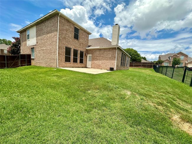 Rear view of property with brick siding, a chimney, a patio, and a fenced backyard | Image 22