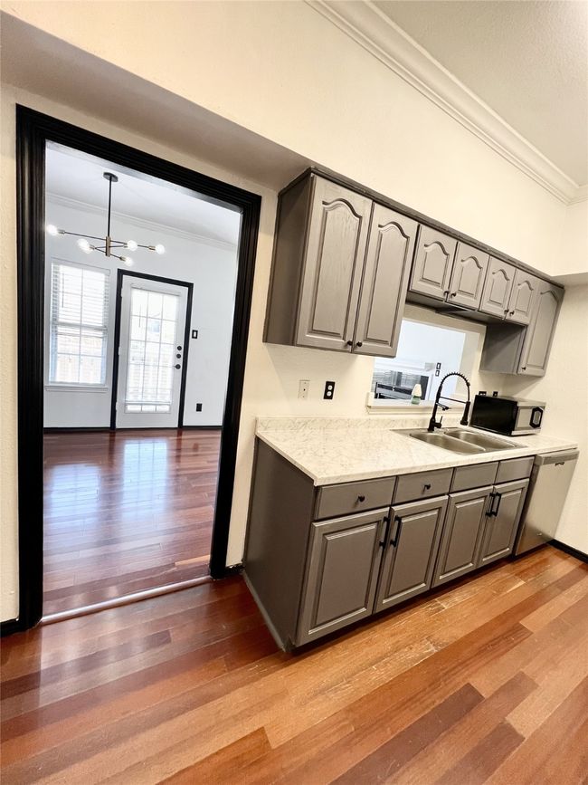 Kitchen with ornamental molding, gray cabinets, a chandelier, light countertops, and a sink | Image 10