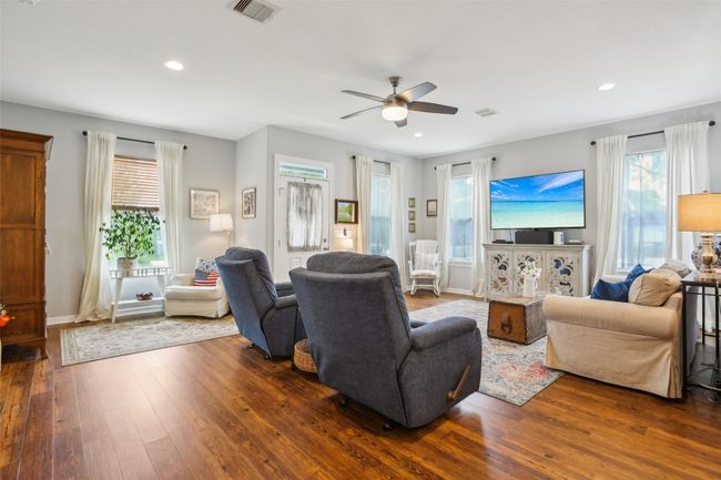 Living room featuring visible vents, ceiling fan, a wealth of natural light, and wood plank laminate flooring | Image 8