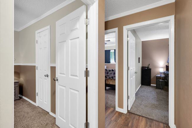 Corridor featuring a textured ceiling, wood finished floors, ornamental molding, and carpet flooring | Image 18