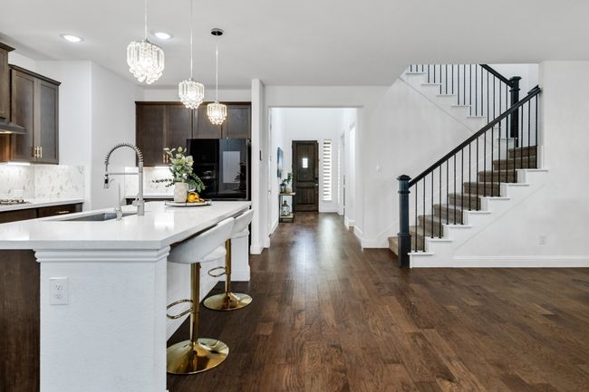 Kitchen featuring dark brown cabinetry, hanging light fixtures, sink, and black fridge | Image 5