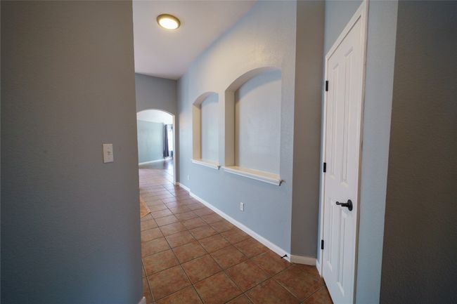 Corridor with dark tile patterned floors, arched walkways, and baseboards | Image 4
