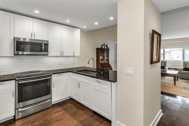 Kitchen with appliances with stainless steel finishes, a sink, dark wood-style flooring, dark countertops, and recessed lighting | Image 9