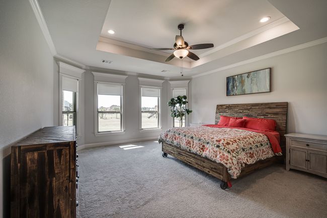 Bedroom with ceiling fan, a raised ceiling, carpet, and crown molding | Image 16