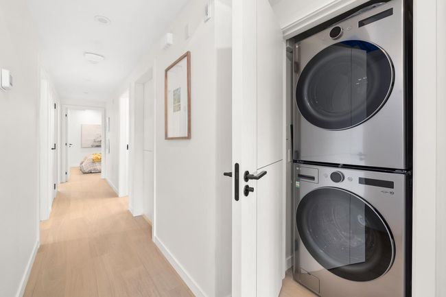Laundry room featuring light wood finished floors, baseboards, stacked washer and clothes dryer, and laundry area | Image 21