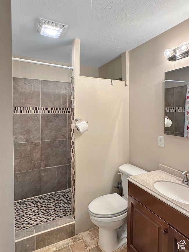 Bathroom featuring a tile shower, toilet, and vanity | Image 22