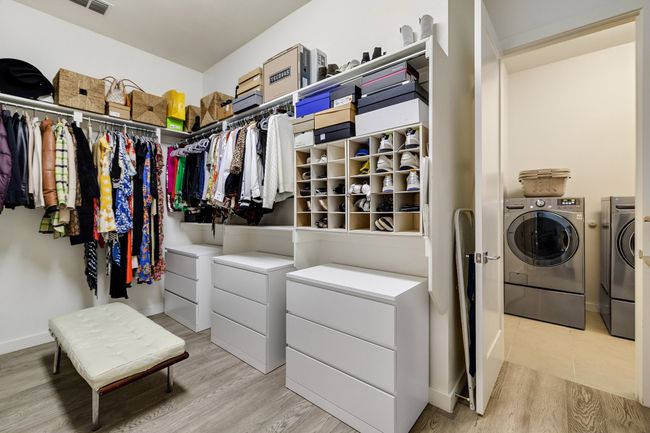 Walk in closet featuring washing machine and dryer and light wood-type flooring | Image 26