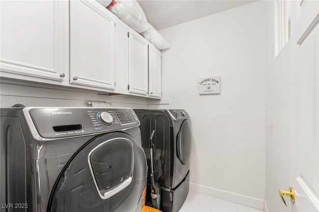 Laundry room featuring washer and clothes dryer, cabinet space, baseboards, and light tile patterned floors | Image 25