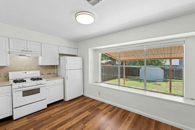 Kitchen featuring white appliances, white cabinets, light countertops, dark wood finished floors, and under cabinet range hood | Image 10