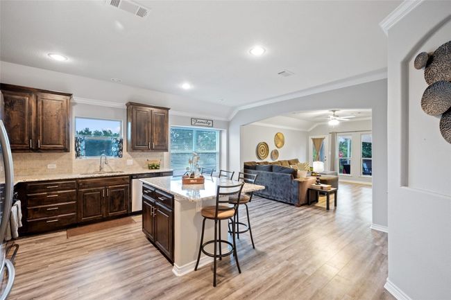 Kitchen with a sink, a breakfast bar area, stainless steel dishwasher, crown molding, and dark brown cabinets | Image 6