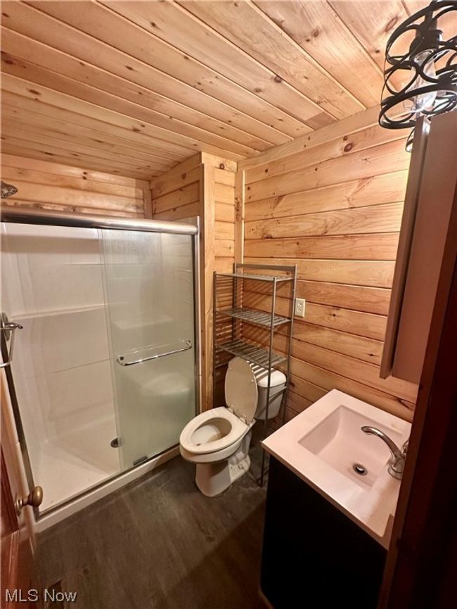 Bathroom featuring hardwood / wood-style flooring, vanity, toilet, a shower with door, and wood ceiling | Image 11