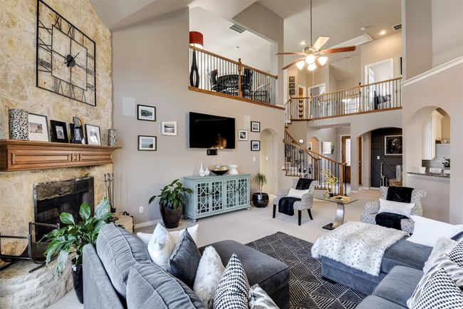 Carpeted living room with ceiling fan, a fireplace, and a high ceiling | Image 12