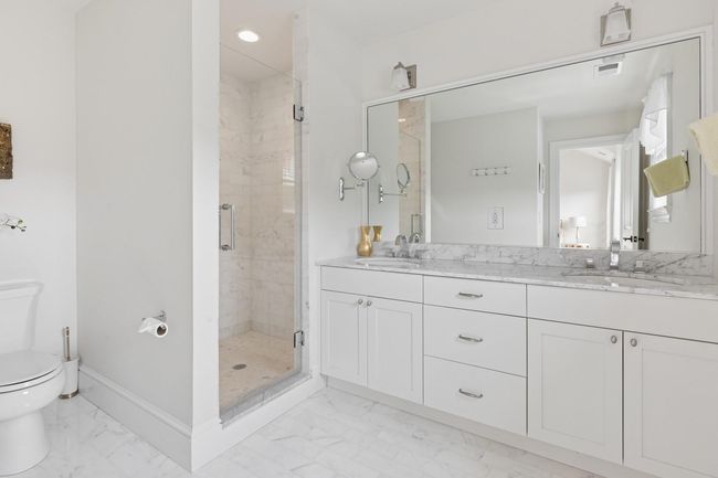Full bathroom with marble finish floors, toilet, double vanity, a shower stall, and baseboards | Image 19
