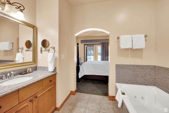 Ensuite bathroom with vanity, a whirlpool tub, tile patterned flooring, ensuite bath, and baseboards | Image 26
