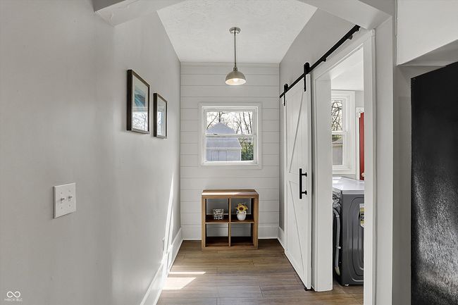 entryway featuring a barn door, wood finished floors, a textured ceiling, baseboards, and washer / clothes dryer | Image 21