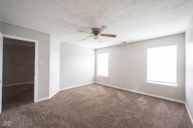 carpeted spare room featuring a textured ceiling, visible vents, baseboards, and ceiling fan | Image 33