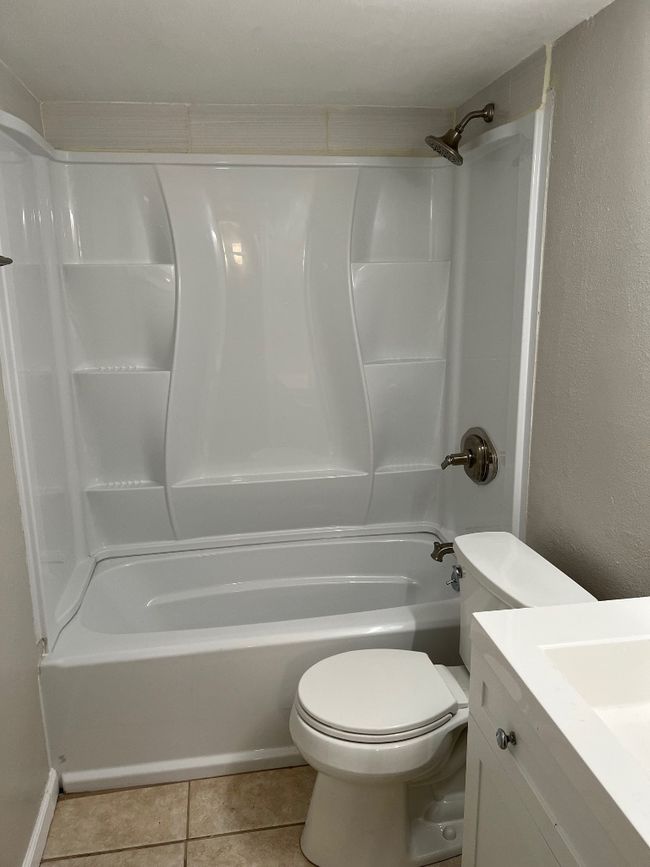 Bathroom with washtub / shower combination, tile patterned flooring, vanity, and toilet | Image 16