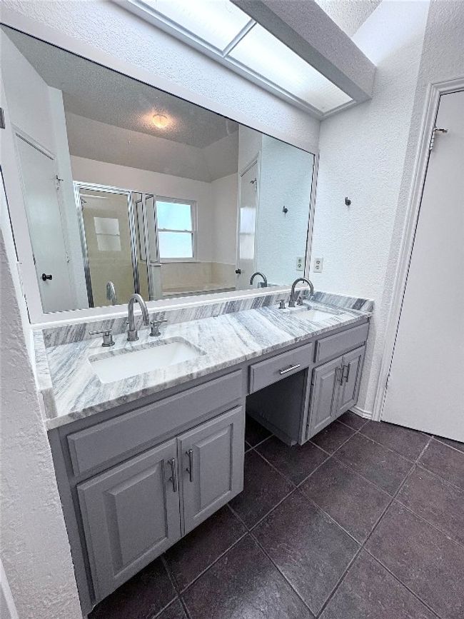 Bathroom featuring a textured wall, a stall shower, dark tile patterned flooring, double vanity, and a textured ceiling | Image 16