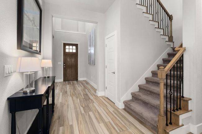 Foyer with a soaring ceiling and light wood like tile floors and stairway | Image 23