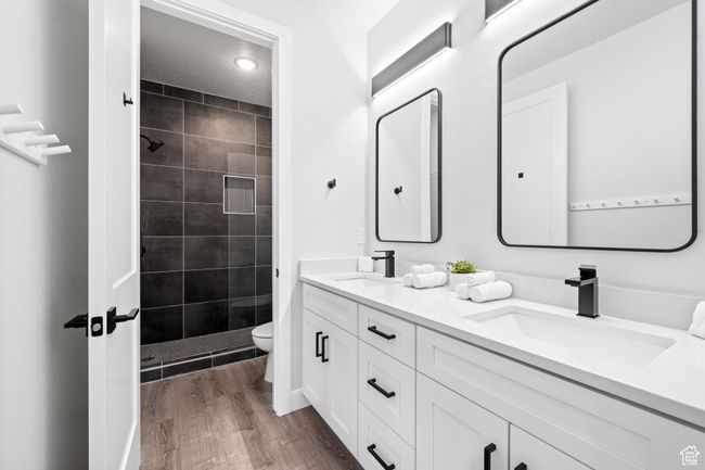 Bathroom with toilet, tiled shower, hardwood / wood-style flooring, and vanity | Image 25