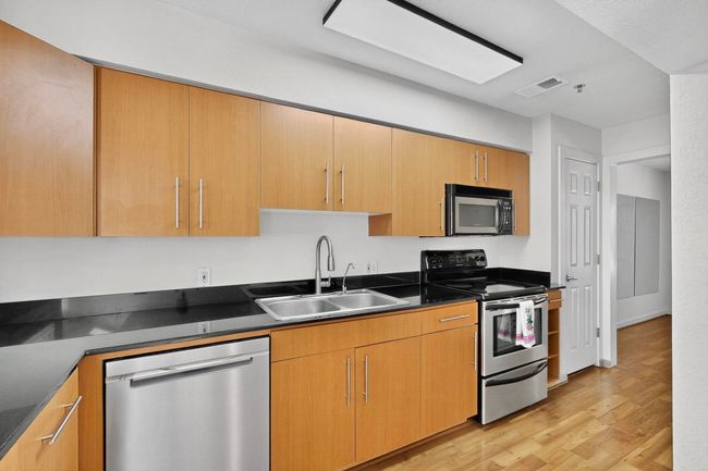 Kitchen with stainless steel appliances, light wood finished floors, dark stone countertops, and modern cabinets | Image 18