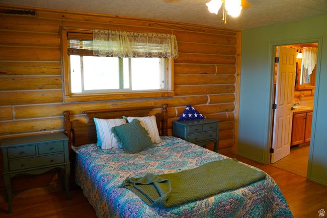 Bedroom with log walls, light wood finished floors, a textured ceiling, and ensuite bathroom | Image 15