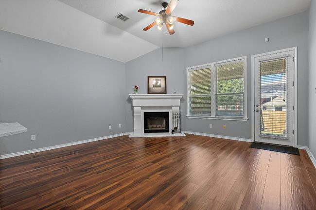 Living room featuring ceiling fan, a fireplace with raised hearth, dark wood-type flooring, vaulted ceiling, and baseboards | Image 14