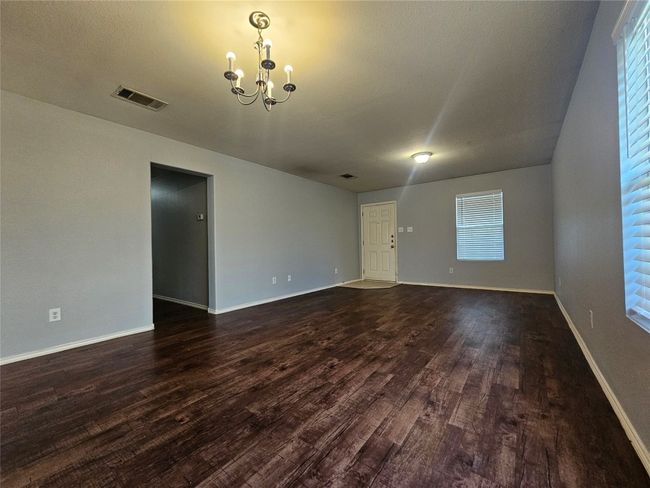 Unfurnished living room featuring a chandelier, dark wood-type flooring, and healthy amount of natural light | Image 9