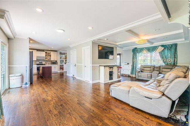 Living area with recessed lighting, crown molding, dark wood-style floors, beam ceiling, and coffered ceiling | Image 24