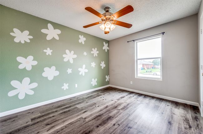Unfurnished room with wood finished floors, baseboards, a ceiling fan, and a textured ceiling | Image 20