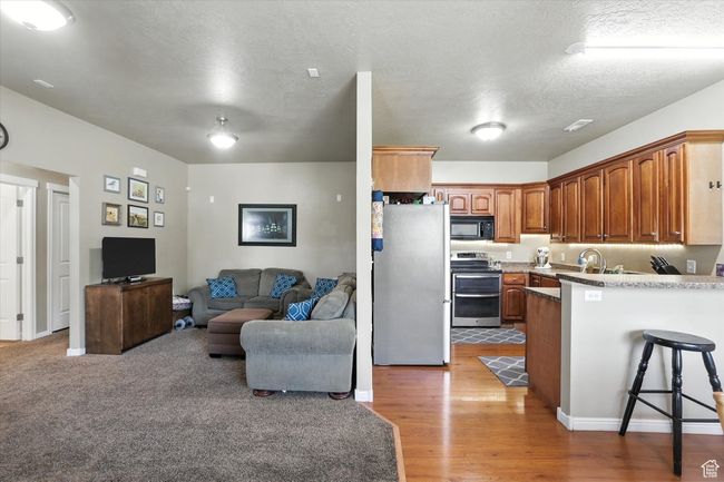 Kitchen with stainless steel appliances, a peninsula, open floor plan, a kitchen breakfast bar, and light wood finished floors | Image 5