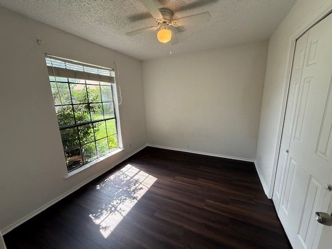 Empty room featuring wood finished floors, a ceiling fan, and a textured ceiling | Image 11