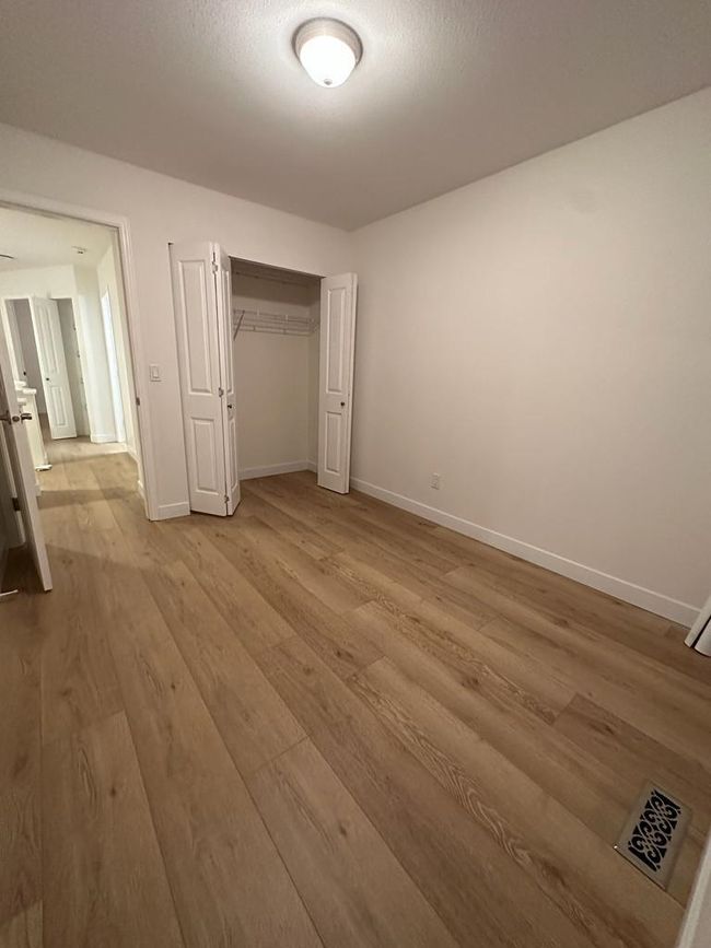 Unfurnished bedroom with wood finished floors, baseboards, a closet, and visible vents | Image 11