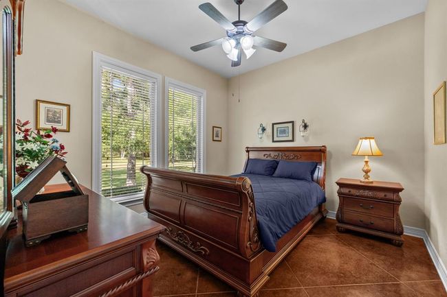 The 3rd bedroom with a ceiling fan and large windows looking onto the views of the outdoors. | Image 31