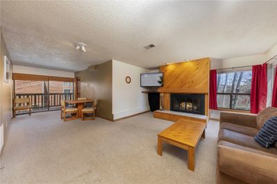 Living room with a wealth of natural light, a textured ceiling, and a wood burning fireplace. | Image 3