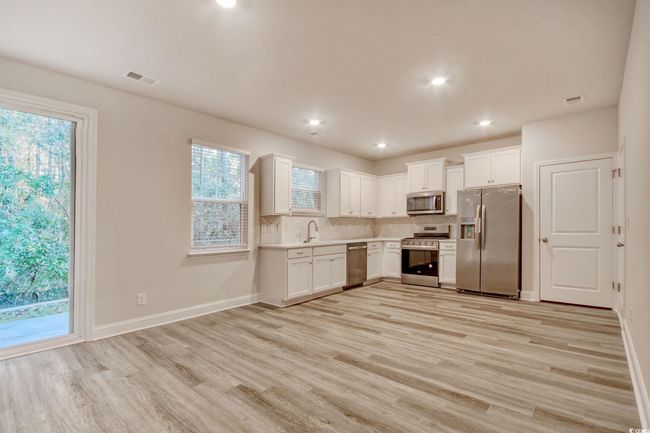 Kitchen featuring appliances with stainless steel finishes, tasteful backsplash, sink, light hardwood / wood-style flooring, and white cabinetry | Image 11