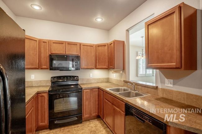 Kitchen featuring black appliances, light countertops, brown cabinets, and recessed lighting | Image 7