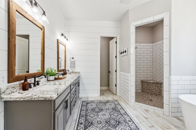 Step into the large primary bathroom, featuring shiplap walls, convenient dual sinks, beautiful granite countertops, and generous storage solutions. | Image 19